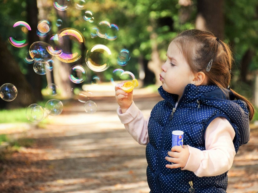 Cute girl is playing with soap bubble